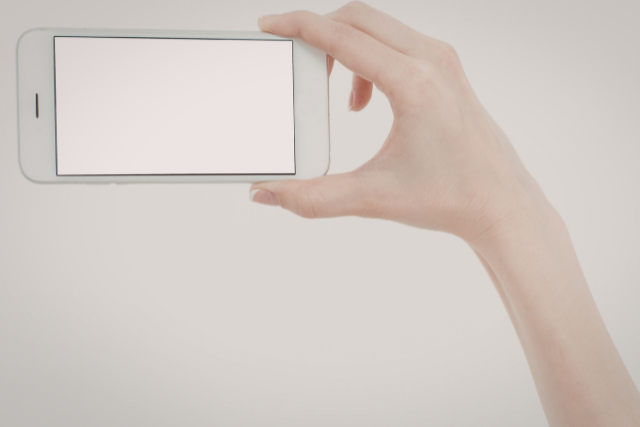 白い画面のスマホを持つ手