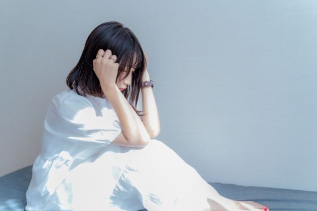白い服を着た女性が頭を抱えて座り込んでいる