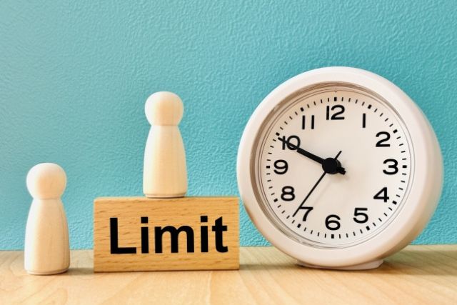 アナログ時計とLimitと書かれた木のブロック・人型の置物