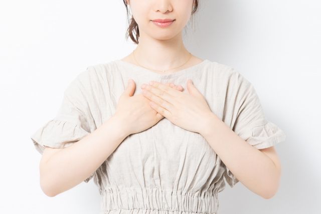 胸に両手を当てる女性の胸元