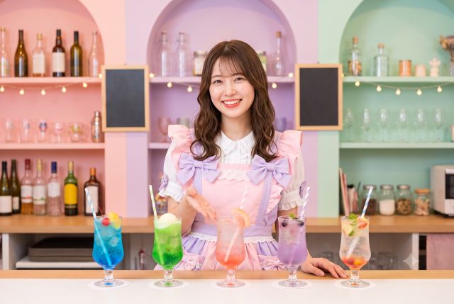 色々な色のドリンクを並べるメイド服の女性