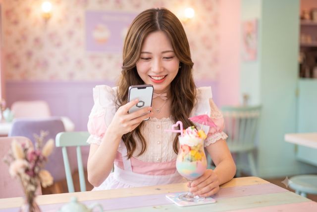 携帯でドリンクを撮るメイド服の女性