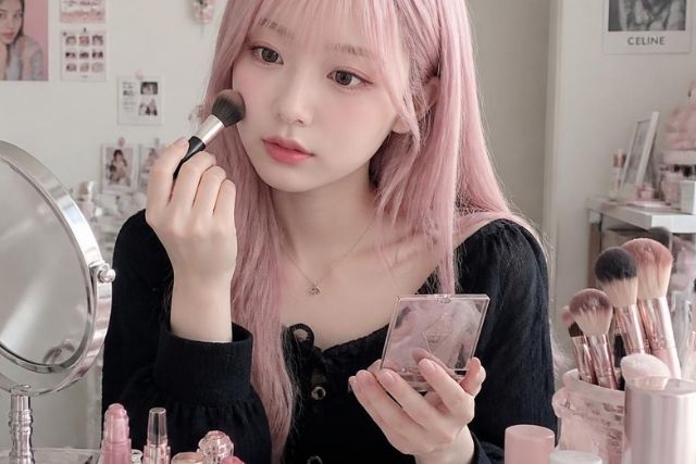 化粧をするピンク色の髪の毛の若い女性