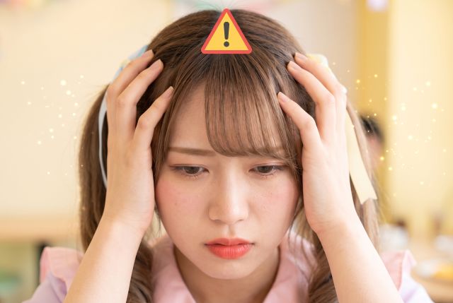 頭を抱えるツインテールの女性