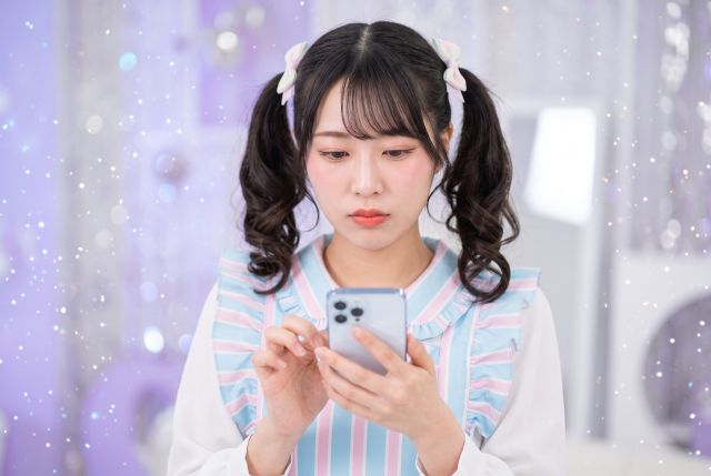 携帯を触るメイド服の女性